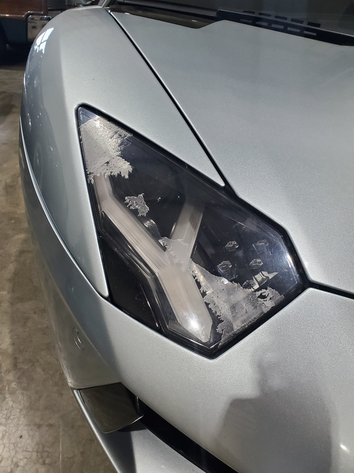Picture of the headlight on a Lamborghini Aventador before headlight restoration was performed by headlight cleaners mobile car detailing
